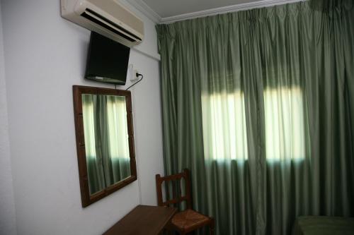 a room with a mirror and a window with green curtains at Hostal Santa Barbara in Socuéllamos