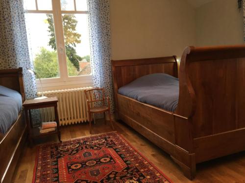 ein Schlafzimmer mit zwei Betten und einem Teppich und einem Fenster in der Unterkunft Maison familiale rénovée, proche châteaux, grand jardin, 5 chambres, équipements inclus, animaux acceptés - FR-1-491-436 in Dhuizon