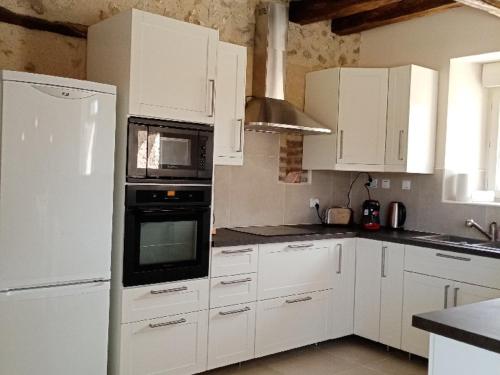 a kitchen with white cabinets and a white refrigerator at Gîte Villedieu-le-Château, 5 pièces, 10 personnes - FR-1-491-432 in Villedieu-le-Château