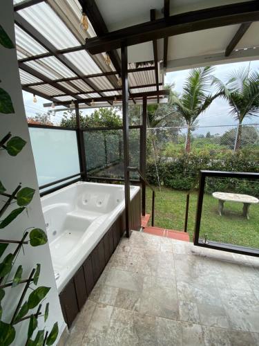 a bath tub in a room with a large window at Finca Hotel 12 Palmas- Aeropuerto JMC in Rionegro