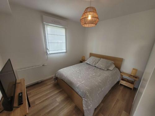 - une chambre avec un lit, une télévision et un lustre dans l'établissement Bel appartement moderne avec jardin et parking privatif - FR-1-675-38, à Wimereux