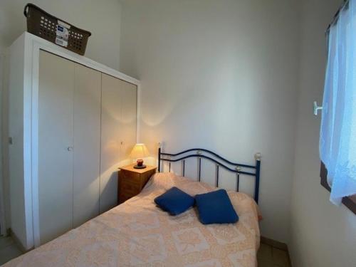 une chambre avec un lit avec deux oreillers bleus dessus dans l'établissement Appartement T2 Mezzanine avec Terrasse, Piscine, Proche Plage et Commerces - Le Barcarès Village - FR-1-782-48, au Barcarès