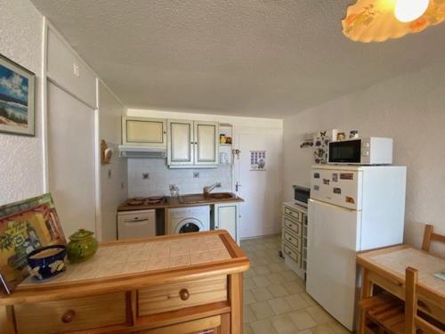 une cuisine avec un réfrigérateur blanc et une table dans l'établissement Appartement en bord de mer avec parking privé, à 50m de la plage - FR-1-782-50, au Barcarès