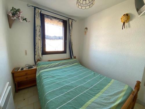 een kleine slaapkamer met een bed en een raam bij Appartement Le Barcarès, 2 pièces, 4 personnes - FR-1-782-50 in Le Barcarès