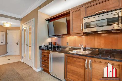 a kitchen with wooden cabinets and a sink and a microwave at MGM Signature-23-811 F1 Track & Strip View Studio in Las Vegas