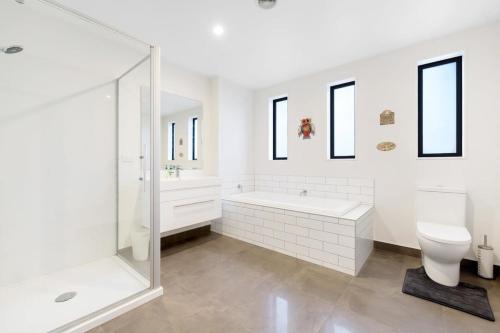 a white bathroom with a tub and a toilet at Grandview Lodge in Wanaka