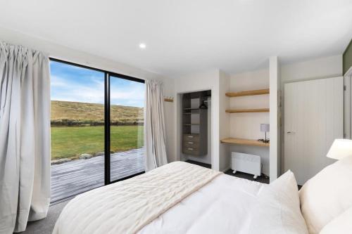 a bedroom with a bed and a large window at Grandview Lodge in Wanaka