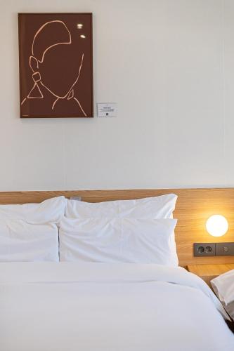 a bed with white pillows and a picture on the wall at Aank Hotel Daejeon Yongjeon 2nd in Daejeon
