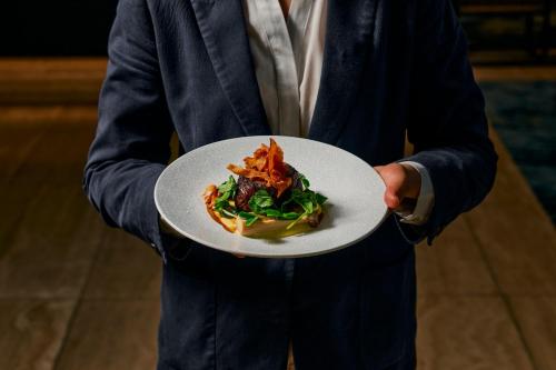 un homme en costume tenant une assiette de nourriture dans l'établissement Hyatt Place Melbourne Essendon Fields, à Melbourne