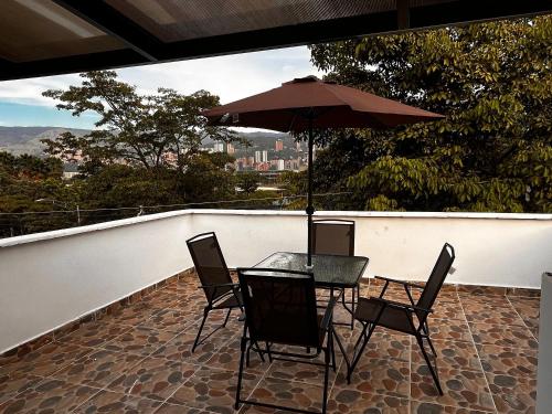 a table and chairs with an umbrella on a balcony at CASA ARKADIA MEDELLÍN in Medellín
