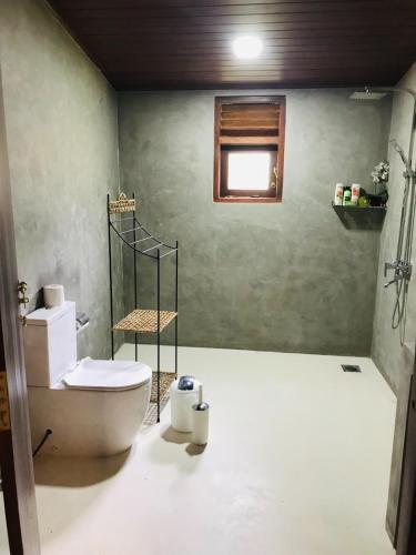 a bathroom with a toilet and a window at Jim's Beach Villas in Hikkaduwa