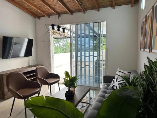 a living room with a couch and chairs and a tv at CASA ARKADIA MEDELLÍN in Medellín