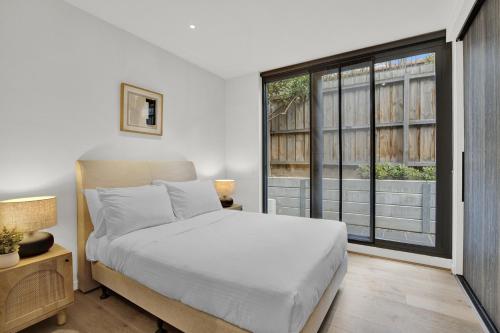 a bedroom with a bed and a large window at Sophisticated 2-Bed by St Kilda Botanical Gardens in Melbourne