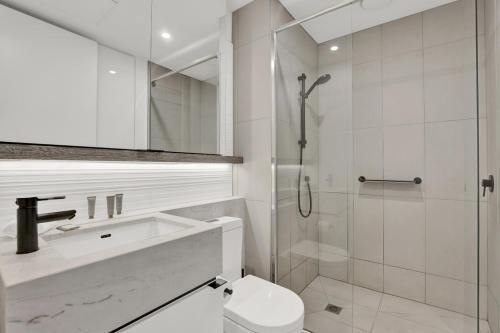 a white bathroom with a toilet and a shower at Sophisticated 2-Bed by St Kilda Botanical Gardens in Melbourne