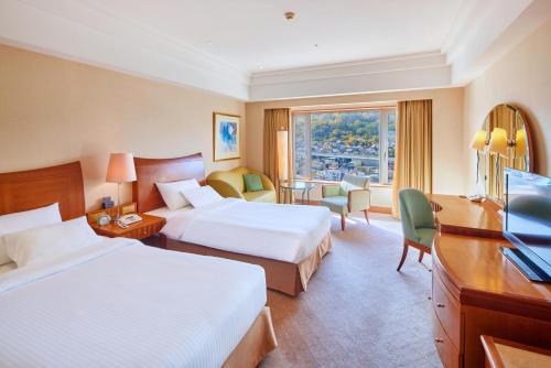 a hotel room with two beds and a television at Grand Park Otaru in Otaru