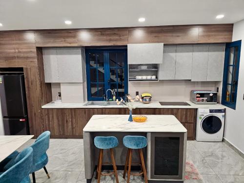 a kitchen with a island with two blue stools at Holiday Villa Novaworld Phan Thiet in Phan Thiet