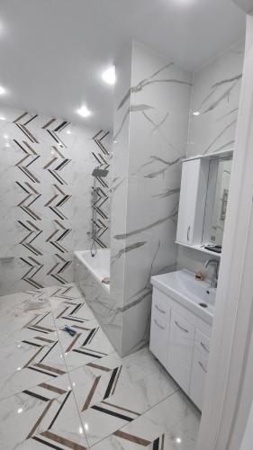 uma casa de banho com um chuveiro, um lavatório e um espelho. em MAEK-KUAT RESIDENCE em Aktau