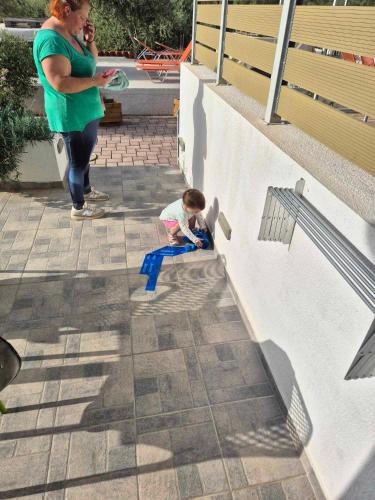 a woman standing next to a child sitting on a bench at tzogias apartments nonna studio in Lassi