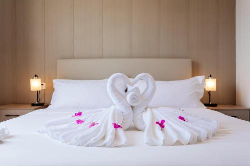 una cama con dos cisnes hechos de toallas en The Q Residence Vientiane en Vientián