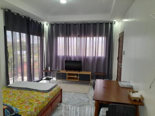 Schlafzimmer mit einem Bett, einem Schreibtisch und einem TV in der Unterkunft Pozorrubio Apartment in Pozorrubio