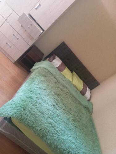 Una cama con una manta verde encima. en Moderno y acogedor apartamento, en Lima