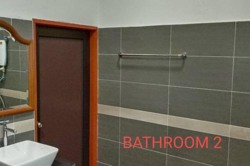 a bathroom with a toilet and a sink and a door at The Bird's Nest Holiday Villa Port Dickson in Port Dickson