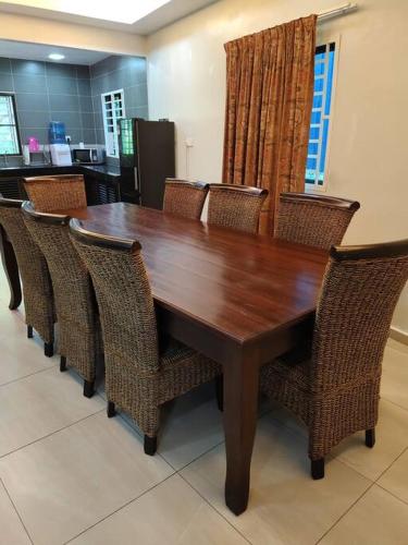 a wooden table with wicker chairs around it in a kitchen at The Bird's Nest Holiday Villa Port Dickson in Port Dickson