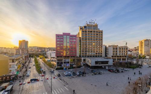 een stad met hoge gebouwen en een straat met auto's bij Cozy Main Square Apartment in Pristina