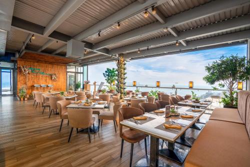 a restaurant with tables and chairs and a large window at Premier Pearl Hotel Vung Tau in Vung Tau