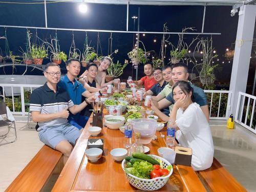 un grupo de personas sentadas alrededor de una mesa con comida en Kazin Homestay Ba vì, en Ba Vì