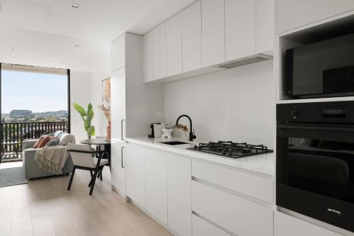a white kitchen with a stove and a microwave at Urban Rest Richmond Swan Street in Melbourne