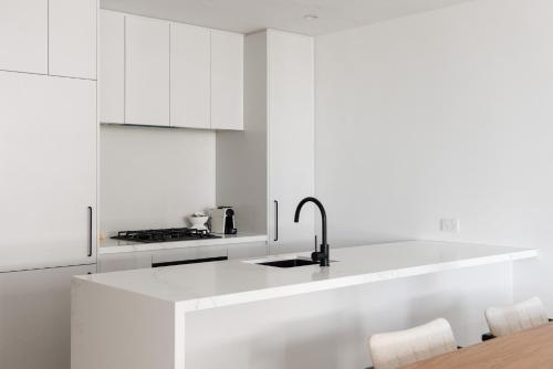 una cocina blanca con armarios blancos y fregadero en Urban Rest Richmond Apartments en Melbourne