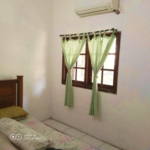 a bedroom with a window with green curtains at PM Family Room in Jakarta