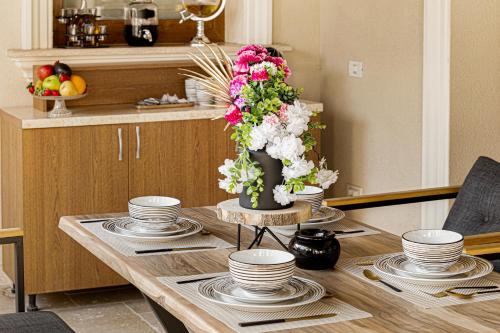 a table with plates and a vase with flowers on it at Sika Grand Palladium Garden & Spa Central Apartment Arad in Arad