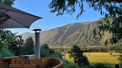 - une terrasse couverte avec un parasol et une vue sur les montagnes dans l'établissement Cabaña Mirador del Valle, à Melipeuco
