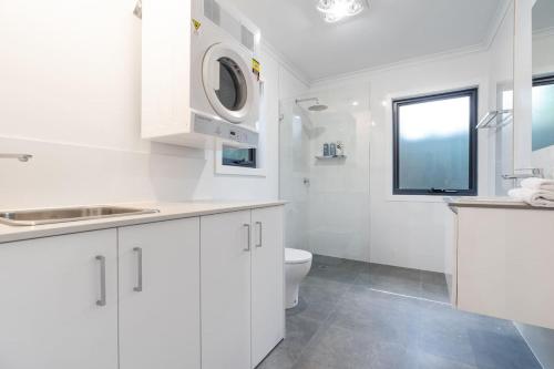 Baño blanco con aseo y lavamanos en Cosy 1 BR unit in Ainslie en Canberra