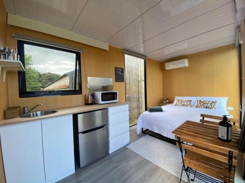 a bedroom with a bed and a kitchen with a sink at Forest Farm Tiny House in Tauranga