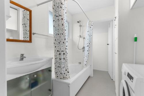 a white bathroom with a shower and a sink at Sunseeker Cottage - Mangawhai Heads Holiday Home in Mangawhai