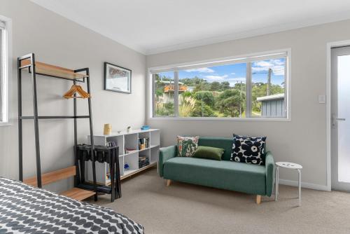 a bedroom with a green couch and a window at Pearl's Embrace - Mangawhai Heads Studio in Mangawhai