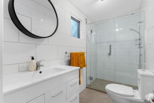 a white bathroom with a sink and a mirror at Pearl's Embrace - Mangawhai Heads Studio in Mangawhai