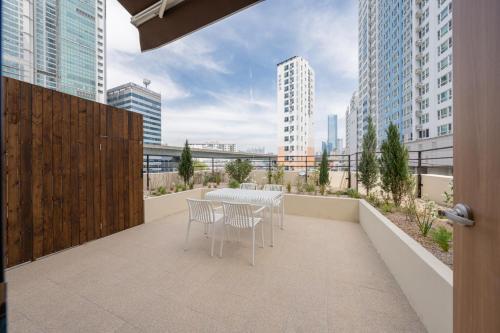 een balkon met een tafel en stoelen en gebouwen bij H-avenue Hotel Munhyeon in Busan