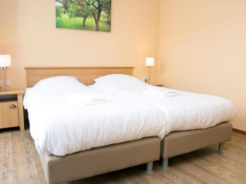 a large white bed in a room with two lamps at Cozy family Bunglow in Zevenhuizen in Zevenhuizen