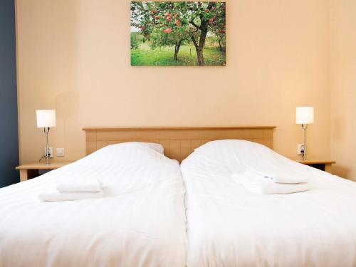 2 weiße Betten in einem Schlafzimmer mit einem Apfelbaum in der Unterkunft Enjoy a 6-person bungalow in Zevenhuizen