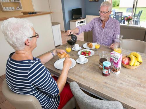 two older people sitting at a table eating food at Cozy family Bunglow in Zevenhuizen in Zevenhuizen