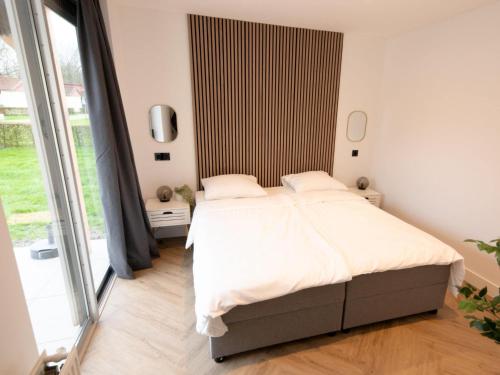 ein Schlafzimmer mit einem Bett und einem großen Fenster in der Unterkunft Luxury bungalow for 6 people in Zevenhuizen
