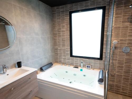 ein Bad mit einer Badewanne und einem Fenster in der Unterkunft Luxury bungalow for 6 people in Zevenhuizen