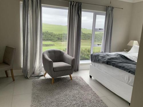 a bedroom with a chair and a bed and a window at Sunshine Modern Retreat in Port Alfred