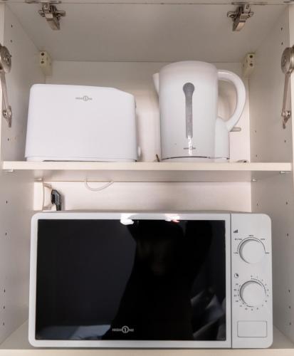 La cuisine est équipée d'un four micro-ondes et d'une bouilloire sur les étagères. dans l'établissement Dreamy Appartement - Disneyland & Paris, à Bussy-Saint-Georges