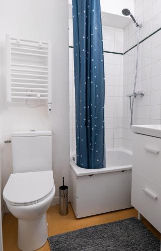 La salle de bains est pourvue de toilettes et d'un rideau de douche bleu. dans l'établissement Dreamy Appartement - Disneyland & Paris, à Bussy-Saint-Georges