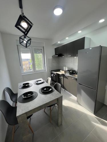 eine Küche mit einem Tisch und einem Kühlschrank aus Edelstahl in der Unterkunft Apartman Central Lux A&D in Bečej